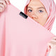 A person holding a pink bamboo and jersey hijab with a visible brand tag.