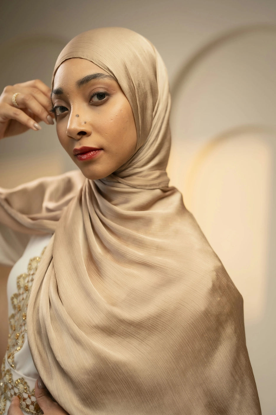 Woman wearing a beige hijab against a neutral background - gold